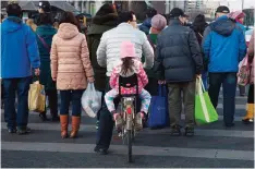  ??  ?? BEIJING, China: A child rides behind a man as they cross the road by bicycle in Beijing, China yesterday. —AP