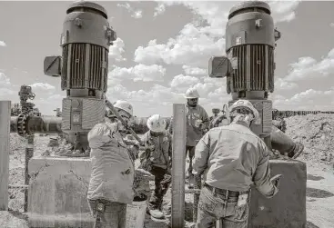  ?? Michael Ciaglo photos / Houston Chronicle ?? Contractor­s work on two water pumps that will push water through a 20-mile pipeline at Layne Christense­n’s new property in Pecos to supply water for hydraulic fracturing operations in the Delaware Basin.