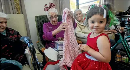  ?? WARWICK SMITH/STUFF ?? Mia Chang, 3, gives 89-year-old Josie Pinker a gift at the adopt a senior Christmas party at Ultimate Care Aroha.