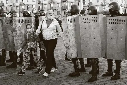  ?? Associated Press ?? A woman and her child walk through a police line during an opposition rally in Minsk, Belarus, to protest election results.
