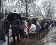  ?? (AP/Evgeniy Maloletka) ?? People line up to collect water, Thursday in Kyiv, Ukraine. Residents of Ukraine’s bombed but undaunted capital clutched empty bottles in search of water and crowded into cafes for power and warmth Thursday, switching defiantly into survival mode after new Russian missile strikes a day earlier plunged the city and much of the country into the dark.