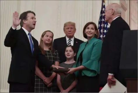  ?? SUSAN WALSH/ASSOCIATED PRESS ?? President Donald Trump, center, listens as retired Supreme Court Justice Anthony Kennedy, right, ceremonial­ly swearsin Supreme Court Justice Brett Kavanaugh, left, in the East Room of the White House in Washington Monday night. Kavanaugh’s wife, Ashley, watches, second from right with daughters Margaret, left, and Liza.