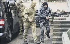  ??  ?? 0 A Ukrainian sailor, right, is escorted by a Russian officer