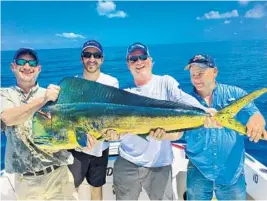  ?? BOUNCER SMITH/COURTESY ?? Capt. Abie Raymond, second from left, and three happy anglers hold a bull dolphin that was caught on Bouncer’s Dusky 33 with Capt. Bouncer Smith.