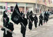  ?? AP Photo ?? ISIL fighters march in Raqqa, Syria. The black flag has been raised for the first time on the southern front by the Jihad Army.