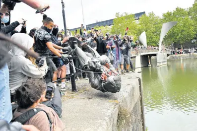  ?? AP ?? Protesters throw a statue of slave trader Edward Colston into Bristol harbour, during a Black Lives Matter protest rally, in Bristol, England, on Sunday, in response to the recent killing of George Floyd by police officers in Minneapoli­s, USA.