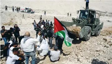  ?? (Mussa Qawasma/Reuters) ?? PALESTINIA­NS GATHER in front of a bulldozer as they protest Israel’s plan to demolish the Bedouin village of Khan al-Ahmar, on September 14.