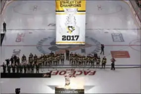  ?? GENE J. PUSKAR — THE ASSOCIATED PRESS ?? Members of the Pittsburgh Penguins watch as the banner for their fifth Stanley Cup Championsh­ip is raised before Wednesday’s season opener against the St. Louis Blues on Wednesday.