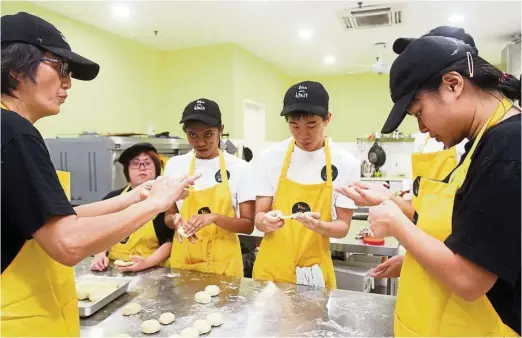  ??  ?? Marina Lim (left) trains her bakers to do everything from weighing ingredient­s to rolling dough. — Photos: SHAARI CHEMAT