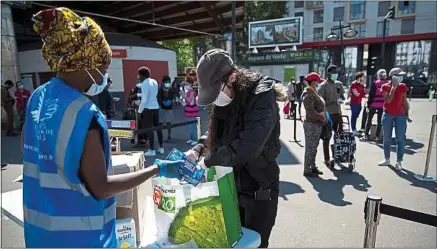  ??  ?? Des bénévoles du Secours populaire distribuen­t des produits de première nécessité à Saint-Denis, le 6 mai.