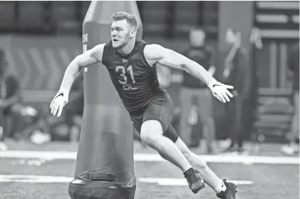  ?? DARRON CUMMINGS/AP ?? Michigan defensive lineman Aidan Hutchinson runs a drill during the NFL scouting combine March 5 in Indianapol­is. Hutchinson may be the top overall pick in Thursday’s NFL draft.