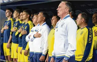  ?? MARCO BUCCO/ LAPRESSE VIA AP ?? Ukraine coach Oleksandr Petrakov (right) and his players sing the national anthem before a training match against Empoli on May 17 in Italy. Ukraine faces Scotland today in a World Cup qualifier.