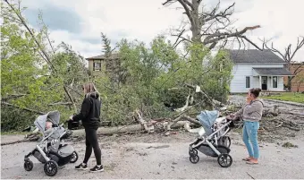  ?? ?? Two women survey damage in Uxbridge caused by Saturday’s storm. We pay now to tackle the climate crisis or future generation­s will pay much more for the damage caused by flooding, high winds, forest fires, ice storms and extreme heat, writes Susan Koswan.