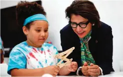  ??  ?? Sylvia Acevedo, right, CEO of the Girl Scouts of the USA, assists a member of the Girl Scouts of Central Maryland as she builds a simple robotic arm during an introducti­on to the world of robotics in Owings Mills, Md.