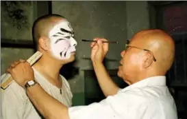  ?? ?? Yang’s teacher, the late Yuan Shihai (right), a noted Peking Opera master, applies makeup to Yang in 1994.