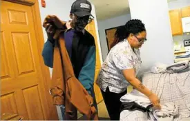  ??  ?? Christina West, right, helps 82-year-old Roosevelt Turner fold his clothes Thursday at his apartment in Garfield.