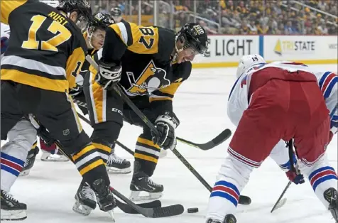  ?? Matt Freed/Post-Gazette ?? Penguins right winger Bryan Rust and center Sidney Crosby fight for the puck against Rangers center Andrew Copp on Monday at PPG Paints Arena.