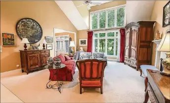  ??  ?? The great room has a cathedral ceiling allowing for a 2-story wall of windows that look out over the backyard and golf course. A gas fireplace has an ornate wood mantel and ceramic-tile surround.