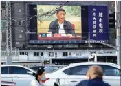  ?? PTI ?? People wearing face masks to protect against the new Coronaviru­s wait to cross an intersecti­on as a large video screen shows Chinese President Xi Jinping speaking in Beijing