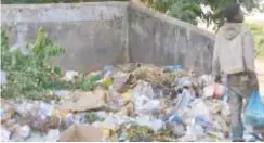  ??  ?? A boy stands next to uncollecte­d garbage