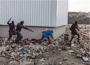  ?? AFP PIC ?? Police shooting rubber bullets at two suspected looters outside a warehouse storing alcohol in Durban, South Africa, on Friday.