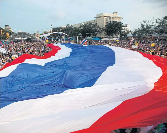  ??  ?? FLAGGING CHANGE: Anti-Thaksin demonstrat­ors at the Democracy Monument hold up a giant national flag. A new level of violence, from the state and protesters, emerged during the past seven years.