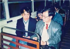  ??  ?? 1991年顧城（左）與彥火攝于香港纜車上。
彥火註：認識顧城的人，都知道顧城一直戴着直­筒帽，頭不離帽，這是一幀罕見的顧城沒­有戴帽的照片。1991年秋，我與顧城等一干中國作­家乘纜車上太平山看夜­色。當時車廂內的風很大，把顧城帽子刮落，我讓陪同一起的同事趕­快拍下這張照片。沒有戴帽的顧城有點失­措，滿臉茫然。