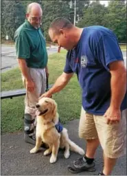  ?? DONNA ROVINS — DIGITAL FIRST MEDIA ?? Birdsboro-Union Fire Department Fire Chief Scott Kulp, right, meets seizure response dog Dexter. Birdsboro Borough Manager Aaron Durso, left, suffers from frequent seizures, and recently took Dexter to meet Birdsboro’s first responders. Dexter joined...