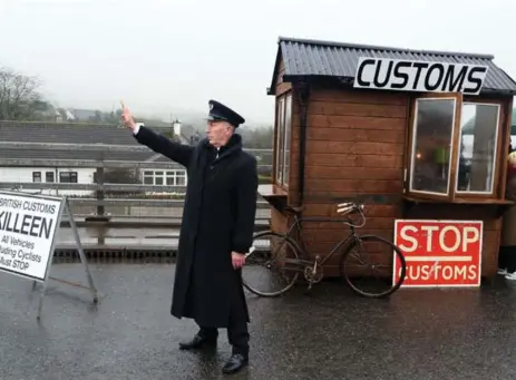  ?? PAUL FAITH/AFP/GETTY IMAGES ?? Demonstrat­ors dressed as custom officials set up a mock customs checkpoint at a border crossing between Northern Ireland the Republic of Ireland to protest against the potential introducti­on of border checks following Brexit.