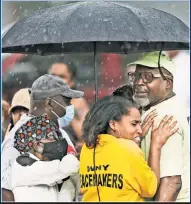  ?? (AP Photo/Joshua Bessex) ?? Bystanders gather under an umbrella as rain rolls in after a shooting at a Buffalo supermarke­t Saturday. Officials said the gunman livestream­ed as he shot 10 people and wounded three more before he was captured by police.