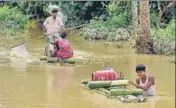  ?? PTI ?? Villagers wade through floodwater­s on a makeshift raft in Nagaon district of Assam on Monday.