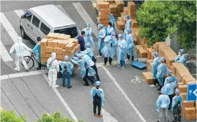  ?? Photo: AFP ?? Health workers push cart carrying food to be sent to a community in Shanghai’s Jing’an district.