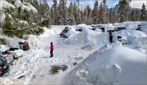  ?? JOEL KEELEr VIA AP ?? This Feb. 6 photo, from video by Joel Keeler shows people attempting to clear cars buried in the parking lot of the showed-in Montecito Sequoia Lodge in Kings Canyon National Park in California’s Sierra Nevada.