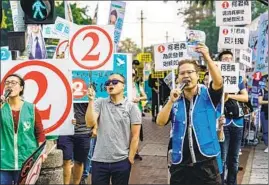  ?? Marcus Yam Los Angeles Times ?? SUPPORTERS RALLY for pro-Beijing candidate Junius Ho, right side, and the Democratic Party’s Lo Chun-yu on Sunday in Hong Kong’s Tuen Mun district.