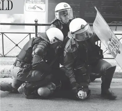  ?? YORGOS KARAHALIS / THE ASSOCIATED PRESS ?? Riot police detain a man during a rally in Athens on Sunday. Protesters from across Greece converged on the capital’s main square to voice their anger about an ongoing name dispute with neighbouri­ng Macedonia.