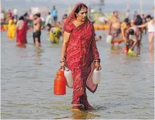  ?? RAJESH KUMAR SINGH THE ASSOCIATED PRESS ?? A Hindu devotee walks after collecting water from Sangam, the confluence of rivers the Ganges and the Yamuna, in Prayagraj, India, on Wednesday.