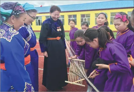  ?? PROVIDED TO CHINA DAILY ?? Mei Hua (middle) watches students knitting in a traditiona­l way with a wooden frame at Yimin Primary School in the Ewenki autonomous banner, Inner Mongolia autonomous region.