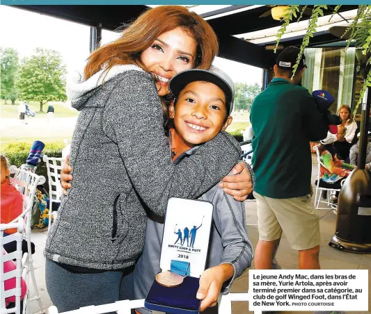  ?? PHOTO COURTOISIE ?? Le jeune Andy Mac, dans les bras de sa mère, Yurie Artola, après avoir terminé premier dans sa catégorie, au club de golf Winged Foot, dans l’État de New York.