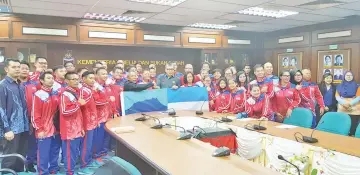  ??  ?? DO YOUR BEST: Awang Damit (left, centre) handing over the State Flag to Terrance with most of the 20th Sopma-bound athletes and officials at Wisma Muis here yesterday.