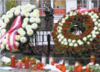  ?? MATTHIAS SCHRADER ASSOCIATED PRESS ?? Un membre des forces de l’ordre surveille le site de l’attaque, au centre-ville de Vienne, où des chandelles et des fleurs ont été déposées en mémoire des victimes.