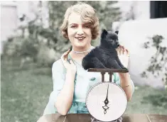  ??  ?? A woman checks her puppy’s weight using old-fashioned scales in this colourised photo