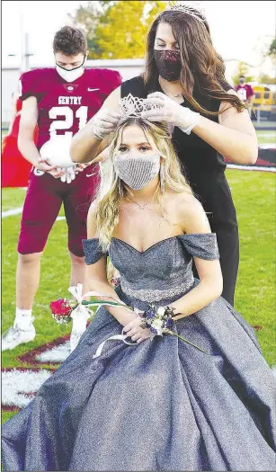  ?? (NWA Democrat-Gazette/Randy Moll) ?? Emma Anderson is crowned the 2020 homecoming queen by Falyn Cordeiro, the 2019 homecoming queen, Oct. 9 during a ceremony in Pioneer Stadium. Gentry senior Seiren Reding, one of the two captains, looks on.