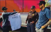  ??  ?? Micah Anderson, LEEF CEO, shows LLF Chief Chris Wilkes and LEEF Lab Director Gary Vandenberg­he a custom-made Willits LEEF T-shirt and hat he gifted the chief.