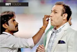  ??  ?? A make-up artiste gives touch-up to Virender Sehwag before the former cricketer begins his commentary stint.