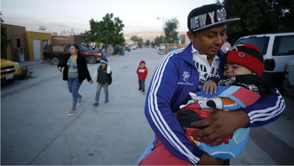  ?? APFILEPHOT­OS ?? WAITING IT OUT: Juan Carlos Perla carries his youngest son, Joshua Mateo, while leaving home in Tijuana, Mexico, for an asylum hearing in July 2019 in San Diego. The Perlas were among the first families sent back to Mexico to await a ruling on their asylumn claim.