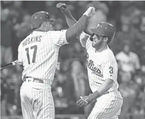  ?? BILL STREICHER/USA TODAY SPORTS ?? Bryce Harper celebrates with Phillies teammate Rhys Hoskins after hitting a home run Sunday against the Braves. Harper returns to his former home field, Nationals Park, on Tuesday.