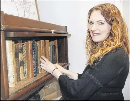  ?? LYNN CURWIN/TRURO DAILY NEWS ?? Ashley Sutherland, the new archivist at the Colchester Historeum, enjoys looking through some of the volumes in the rare and fragile books case.