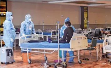  ?? — PTI ?? Health workers attend to a corona patient inside the Shehnai Banquet Hall a Covid care facility in New Delhi on Thursday.