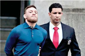  ?? AP Photo/Julio Cortez ?? ■ Ultimate fighting star Conor McGregor, left, is led by an official to an unmarked vehicle Friday while leaving the 78th Precinct of the New York Police Department in the Brooklyn borough of New York. McGregor was arraigned Friday on felony criminal...