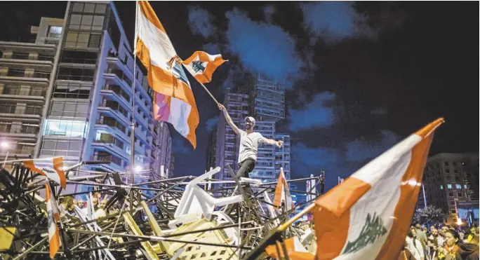  ??  ?? An antigovern­ment protester waves a Lebanese flag in Martyrs’ Square, Beirut.